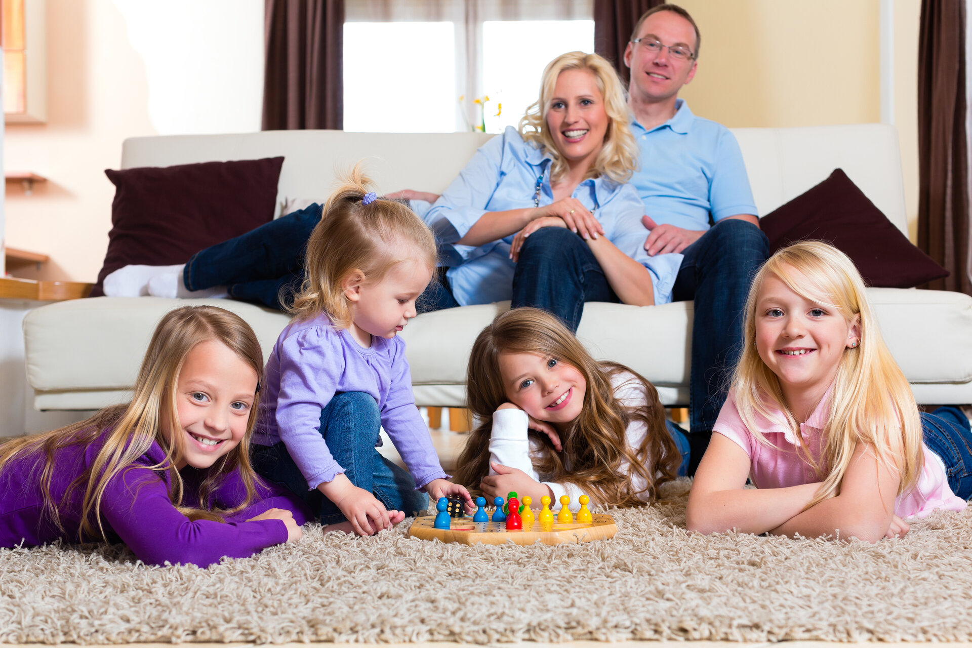 Adults and children gathered around a board game on a carpet